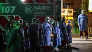 عاملون بقطاع الصحة يقفون بجانب سيارات الإسعاف